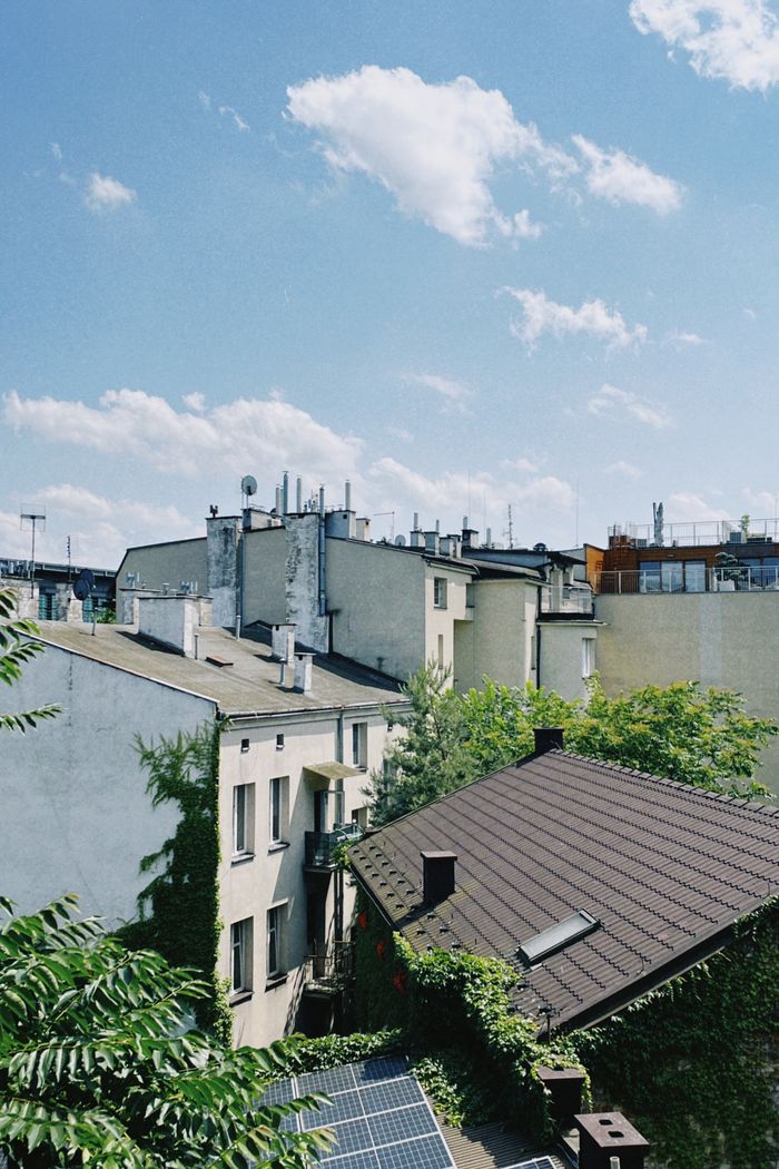 service-03 A sunny view of Kraków rooftops featuring residential buildings and solar panels.