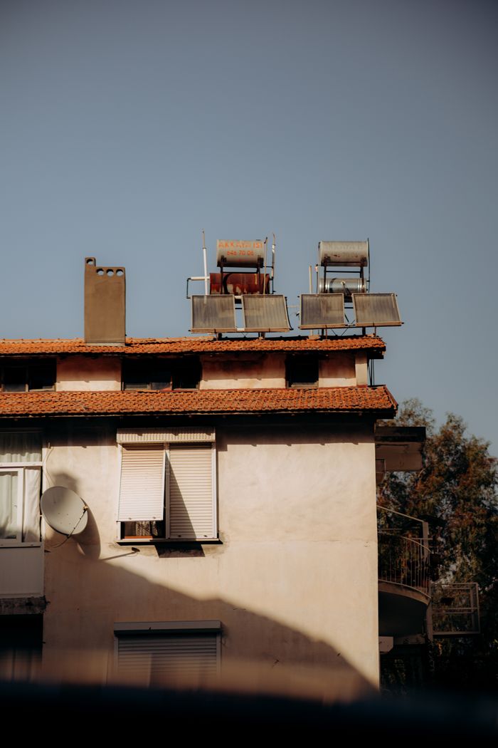 Vintage style building with red roof tiles and solar panels under clear blue sky.