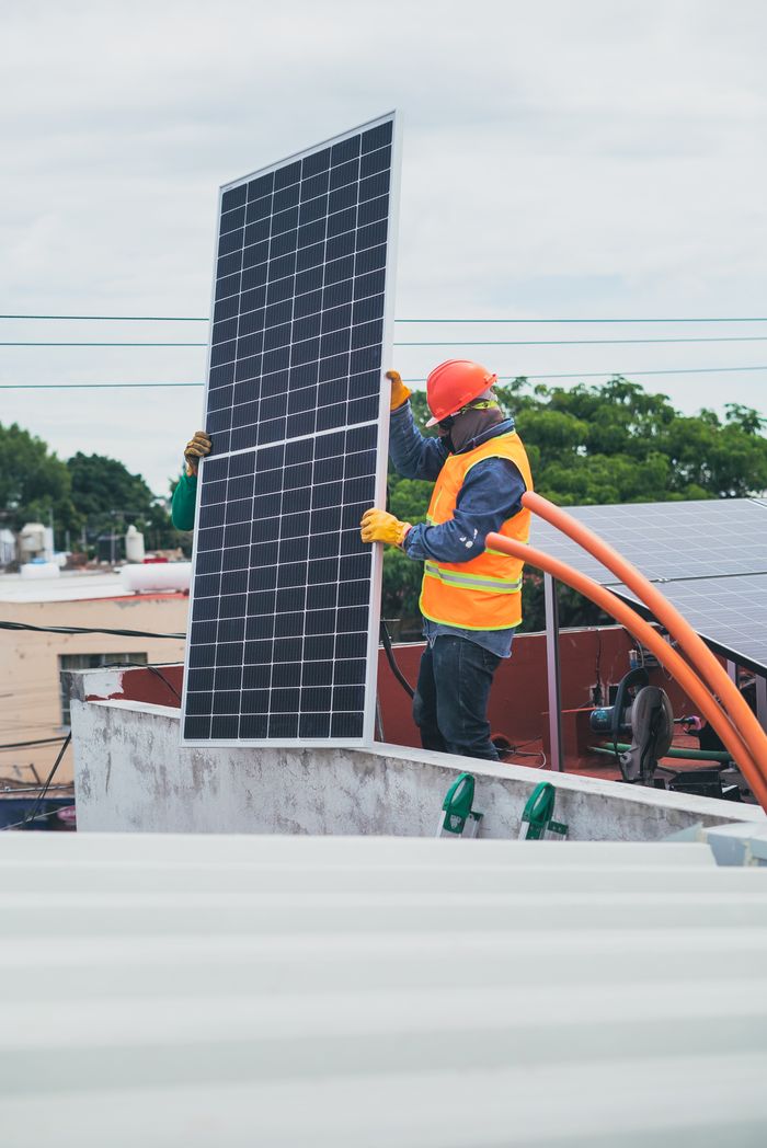 service-06 A technician in safety gear installs a solar panel on a rooftop, promoting renewable energy.