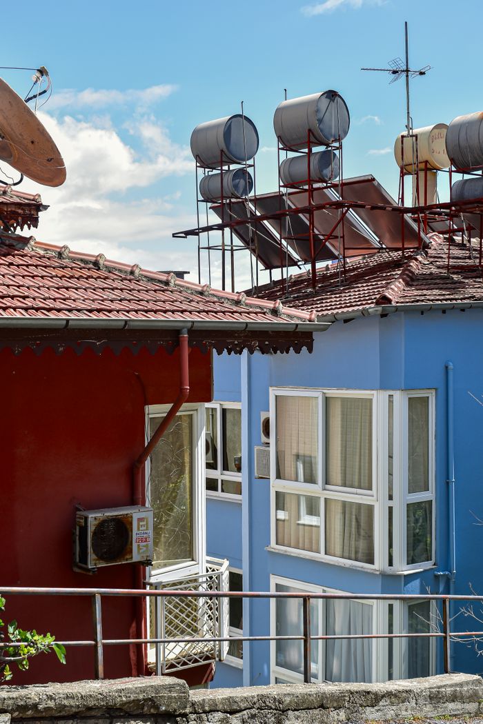 service-05 Colorful rooftops with solar water heaters in sunny urban setting. Ideal for energy or architecture themes.